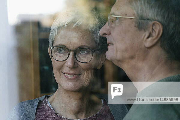 Zuversichtliches älteres Ehepaar schaut aus dem Fenster