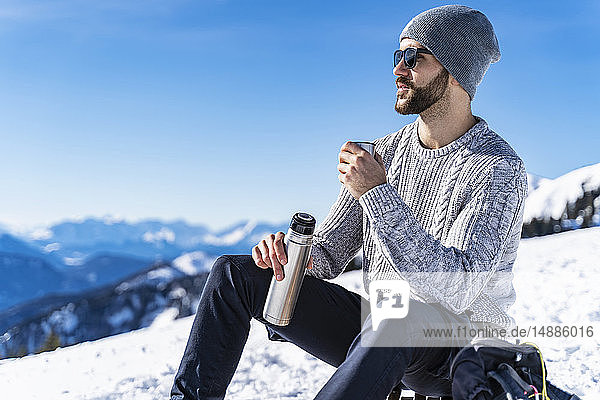 Germany  Bavaria  Brauneck  man in winter in the mountains having a break