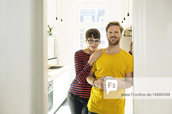 Glückliches Paar lehnt im Türkasten vor ihrer Küche