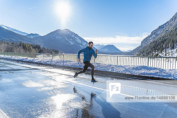 Deutschland  Bayern  sportlicher Mann läuft im Winter auf einer Straße