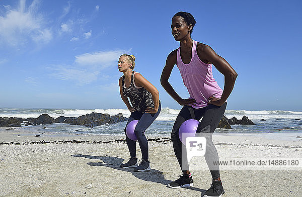 Zwei Frauen bei Fitnessübungen mit Ball am Strand
