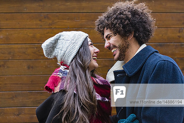 Happy young couple in winterwear in front of wooden wall