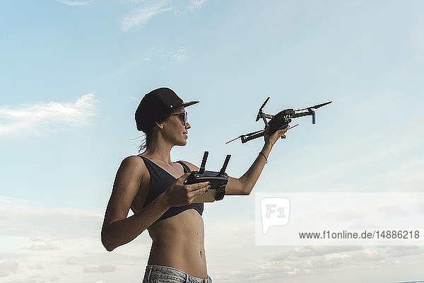 Frau hält Drohne unter Himmel mit Wolken