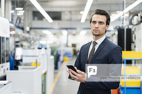 Portrait of businessman with cell phone in a factory