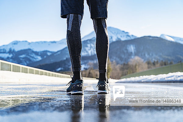 Deutschland  Bayern  Beine eines sportlichen Mannes  der im Winter auf einer Straße steht