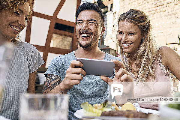 Freunde amüsieren sich auf einer Grillparty und fotografieren mit ihren Smartphones
