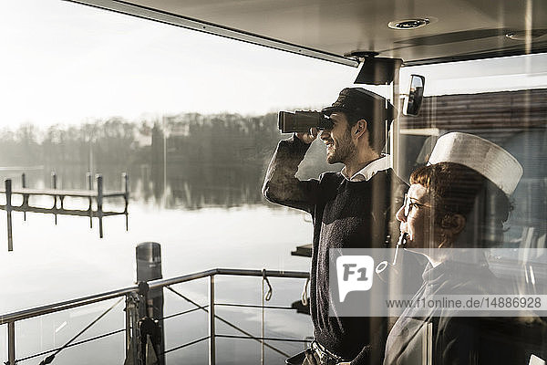 Kollegen  die auf einem Hausboot arbeiten und die Umgebung mit dem Fernglas beobachten