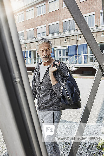 Porträt eines reifen Mannes mit Sporttasche auf dem Weg zum Fitnessstudio