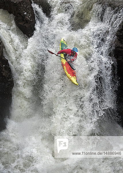 Mann im Kajak auf einem Wasserfall auf einem Fluss