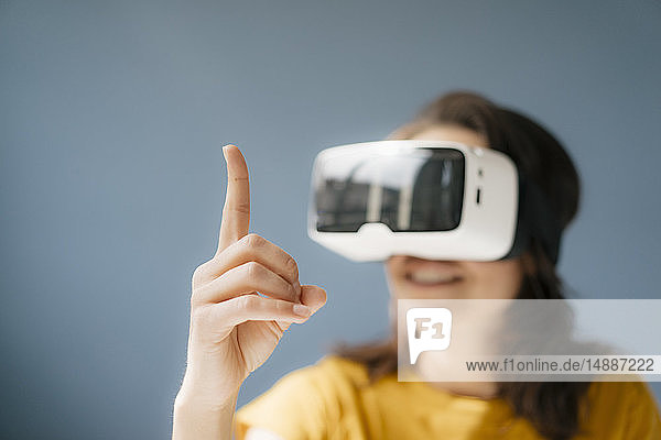 Frau mit VR-Brille  die den erhobenen Finger beobachtet