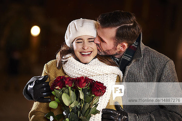 Mann küsst im Winter seine lachende Freundin