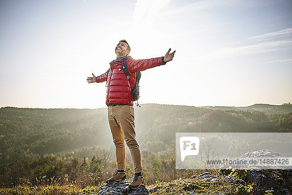 Man on a hiking trip in the mountains standing on rock enjoying the nature
