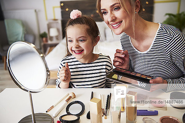 Mother and daughter applying make up together