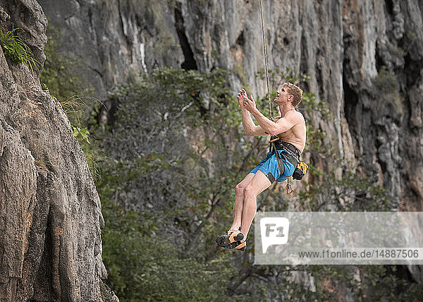 Thailand  Krabi  Lao Liang  barechested climber abseiling from rock wall