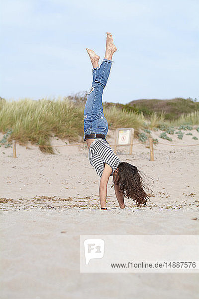 Spanien  Menorca  barfüßige junge Frau beim Handstand am Strand