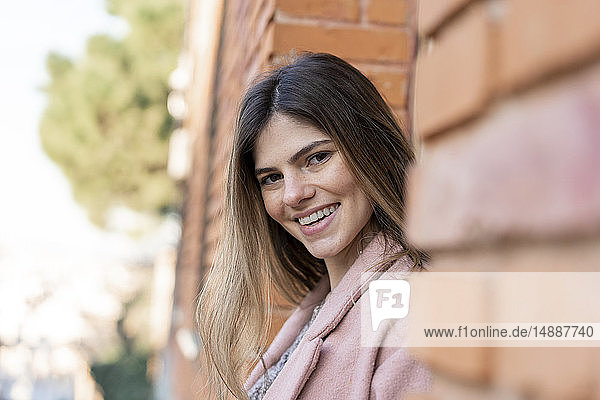 Portrait of a happy young woman at a brick building