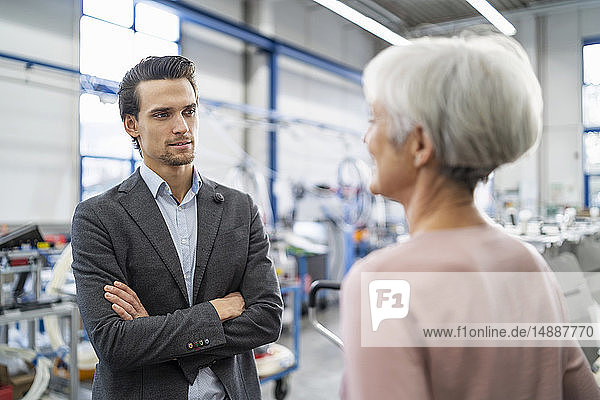 Smiling businessman and senior businesswoman talking in a factory