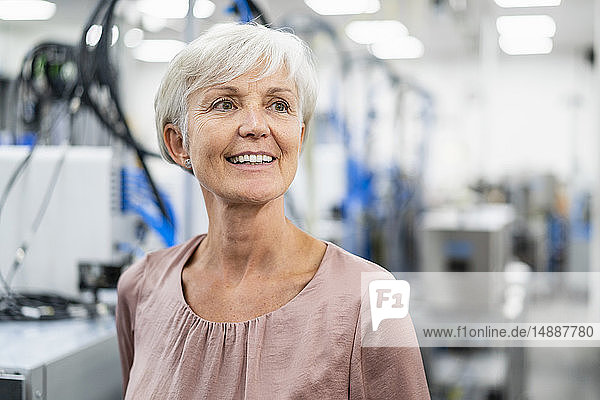 Porträt einer lächelnden älteren Frau in einer Fabrik