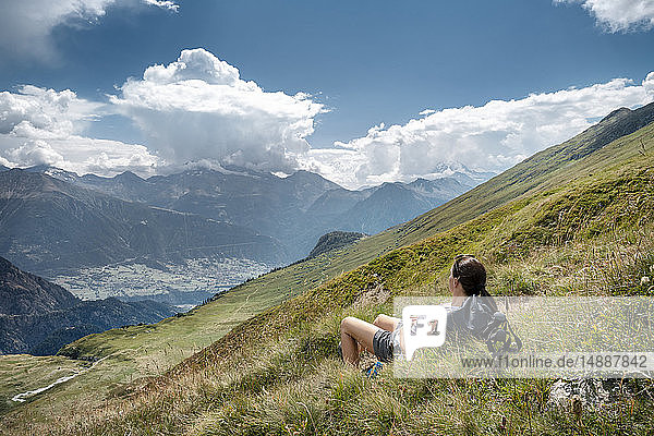 Schweiz  Wallis  Frau auf einer Wanderung in den Bergen Richtung Foggenhorn auf einer Alpweide liegend