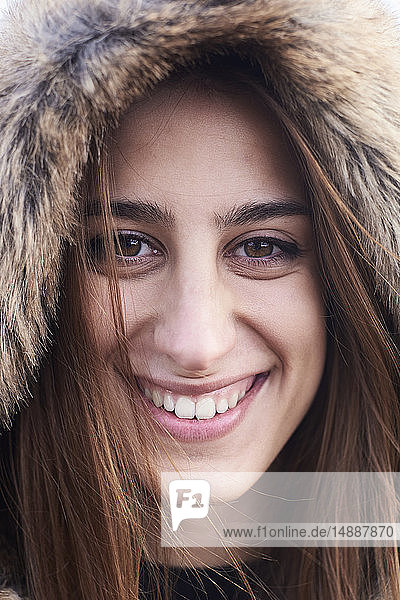 Portrait of happy young woman wearing fur hood