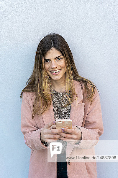 Portrait of a happy young woman holding cell phone