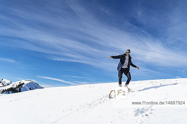 Deutschland  Bayern  Brauneck  Mann auf Schlitten im Winter in den Bergen stehend