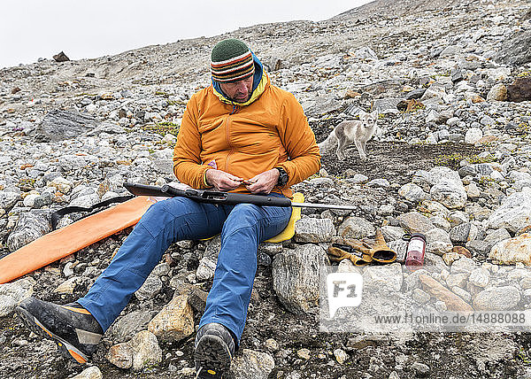 Greenland  Sermersooq  Kulusuk  Schweizerland Alps  man with rifle and arctic fox