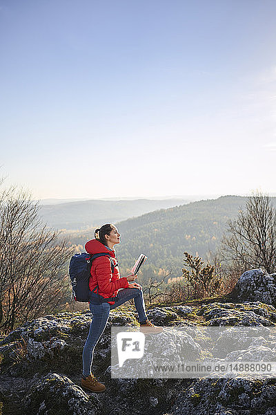 Woman on a hiking trip in the mountains holding map and enjoying beautiful view