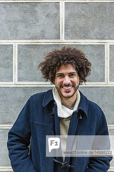 Porträt eines glücklichen jungen Mannes mit lockigem Haar
