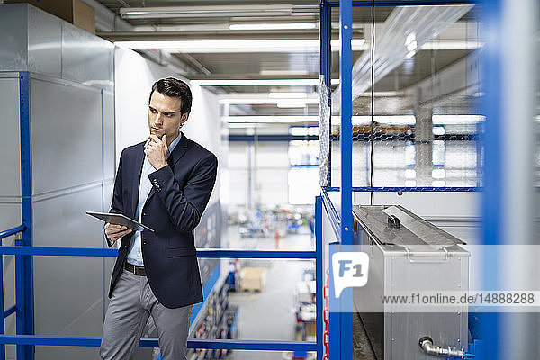 Thoughtful businessman with tablet in a factory