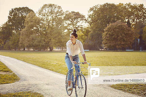 Junge Frau fährt Fahrrad in einem Park