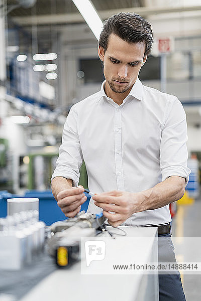 Geschäftsmann  der ein Werkstück in einer Fabrik untersucht