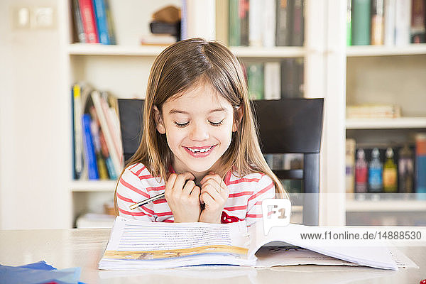 Portrait of happy little girl doing homework