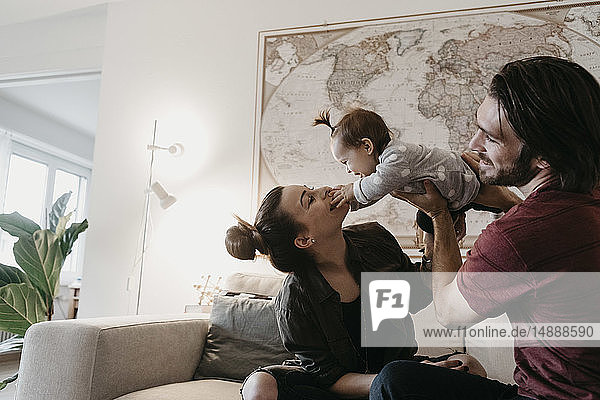 Happy family playing with baby girl in living room at home