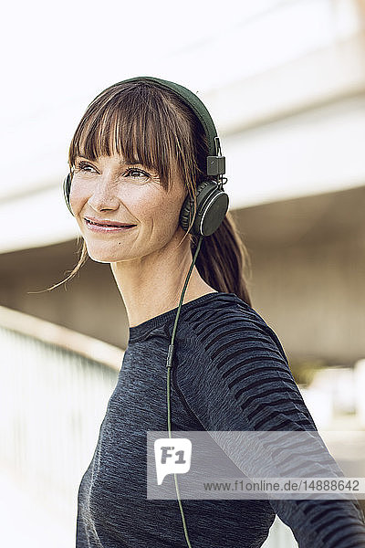 Sportliche Frau mit Kopfhörern  die ihr Fitnesstraining im Freien absolviert