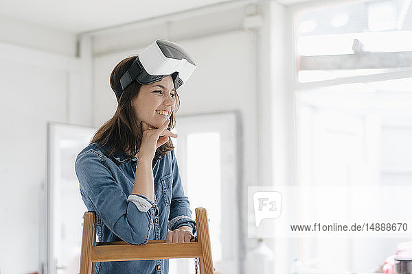 Frau mit VR-Brille  auf Leiter lehnend