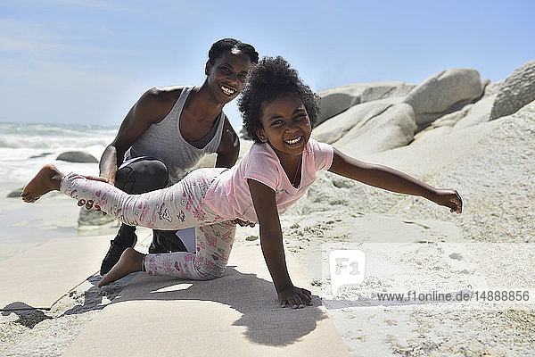 Mother and daughter doing a gymnastic exercise on the beach