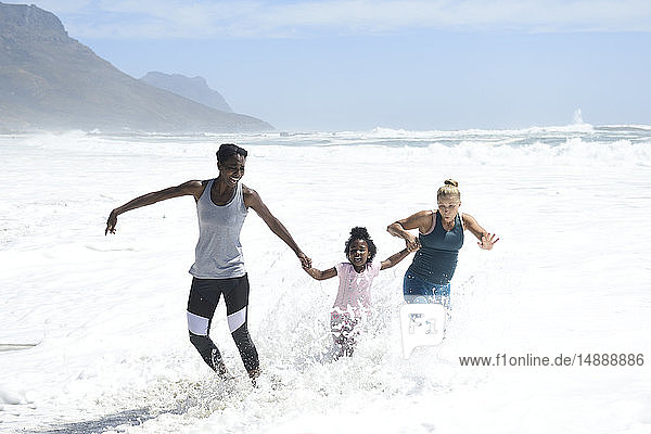 Mother with daughter and friend having fun in surf on the beach