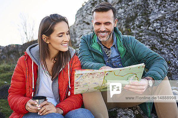 Glückliches Paar auf einer Wanderung in den Bergen macht eine Pause und schaut auf die Karte