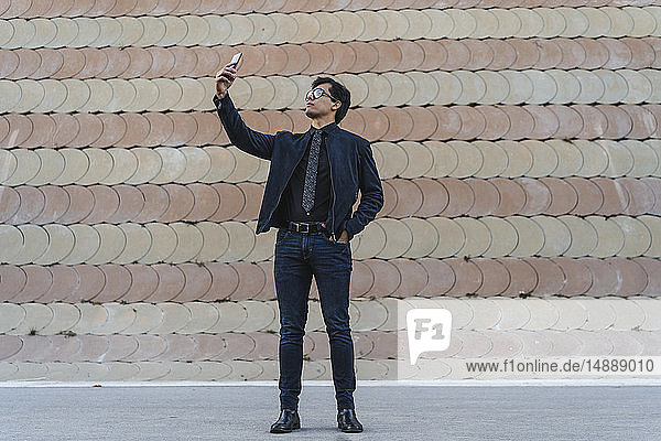 Modischer junger Geschäftsmann nimmt Selfie mit dem Handy