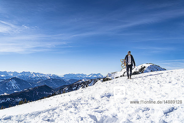 Deutschland  Bayern  Brauneck  Mann mit Schlitten im Winter in den Bergen