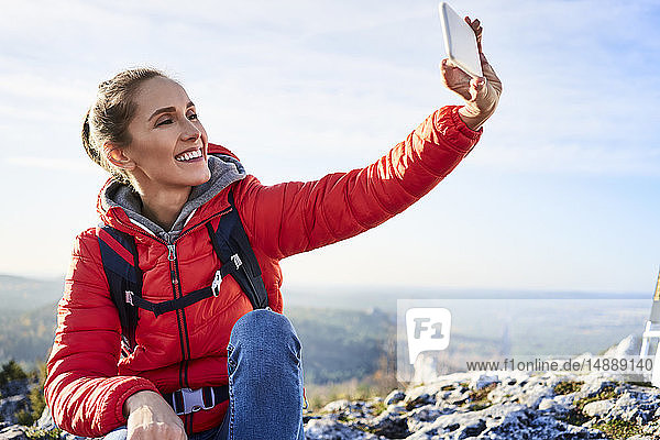 Glückliche Frau geht mit einem Selfie auf eine Wanderung in die Berge