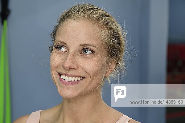 Porträt einer lächelnden jungen blonden Frau in einer Turnhalle