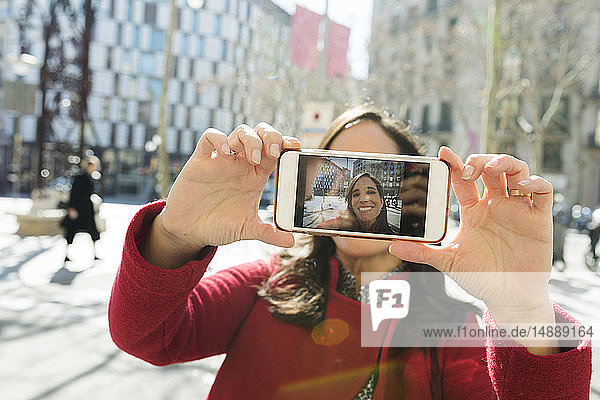 Lächelnde Frau  die in der Stadt ein Selfie macht