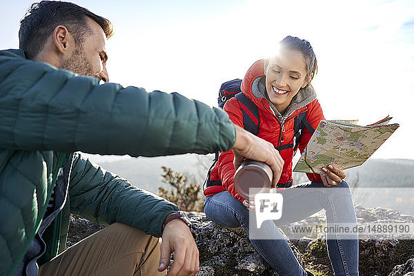 Glückliches Paar auf einer Wanderung in den Bergen bei einem heissen Getränk während einer Pause