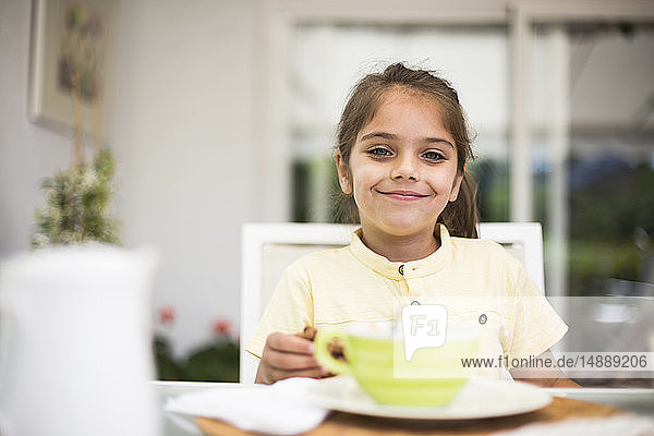 Porträt eines lächelnden kleinen Mädchens beim Frühstück zu Hause