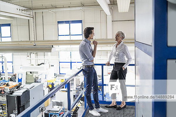 Businessman and senior businesswoman talking in a factory