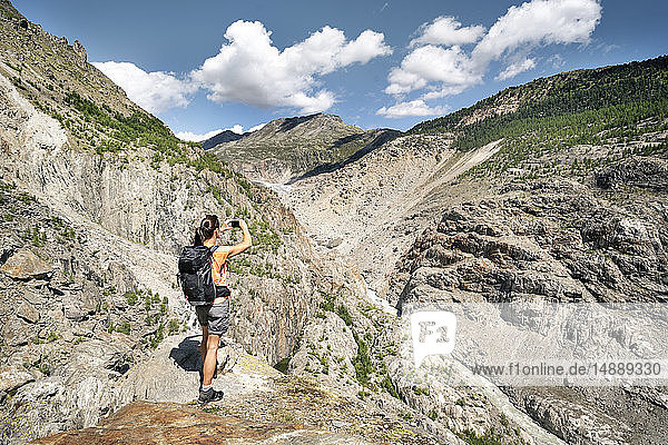 Schweiz,  Wallis,  Frau beim Fotografieren während einer Wanderung in den Bergen am Aletschgletscher