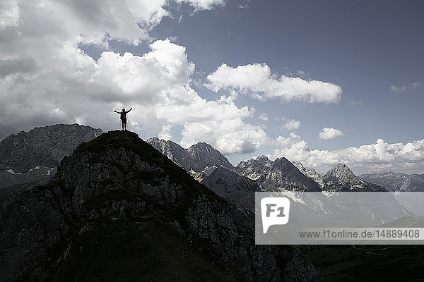 Österreich  Tirol  Silhouette eines auf dem Berggipfel jubelnden Mannes