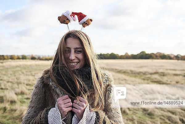 Porträt einer glücklichen jungen Frau mit weihnachtlichem Kopfschmuck auf dem Land